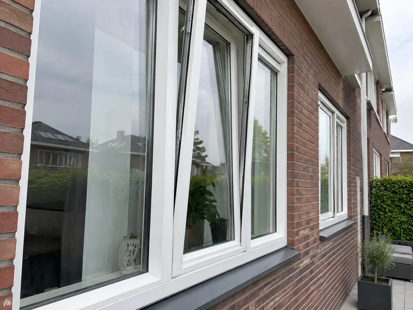 Witte kunststof draaikiepramen in een bakstenen woning